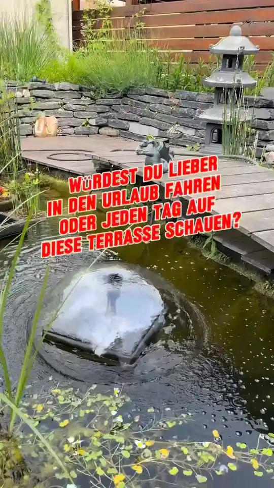 Gartenteich mit Wasserspiel vor einer Natursteinmauer
